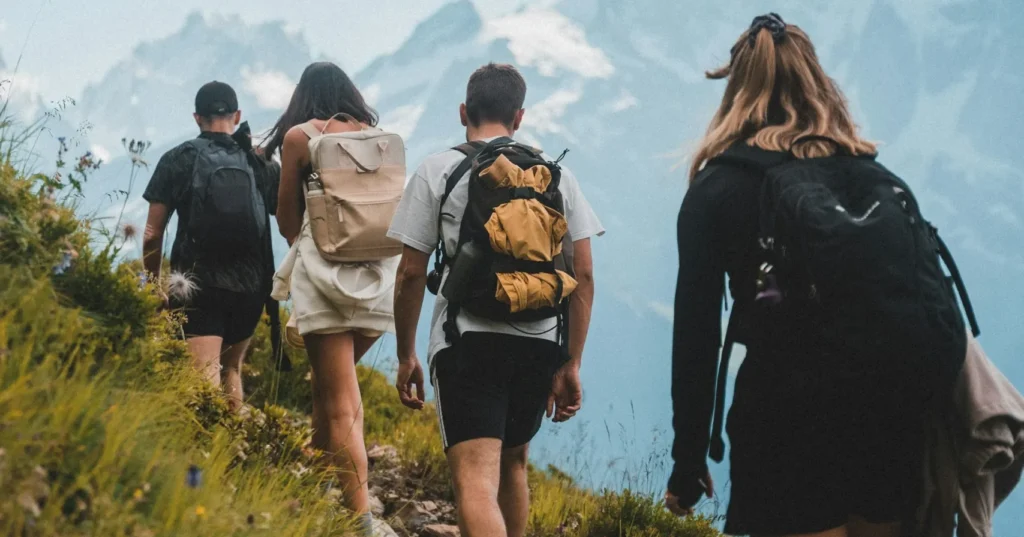A group of people hiking on the mountain by holding baggage on their back.