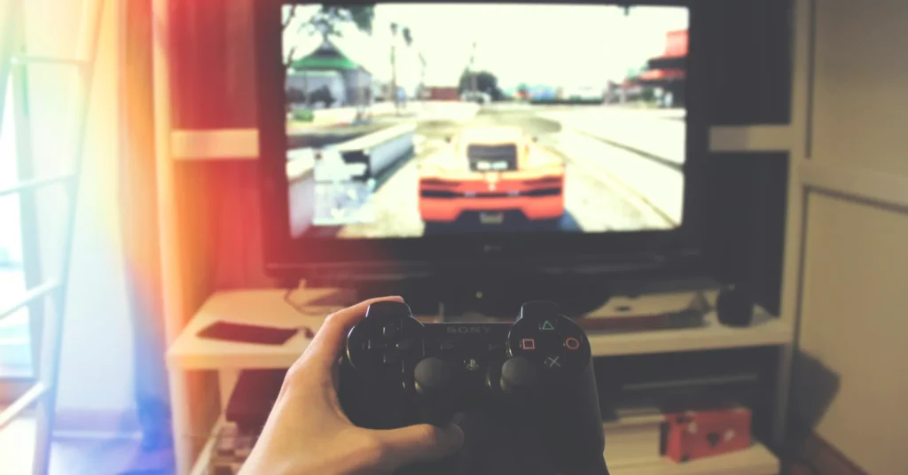 A person holding a controller of PS3 and playing the games of some type of racing cars.