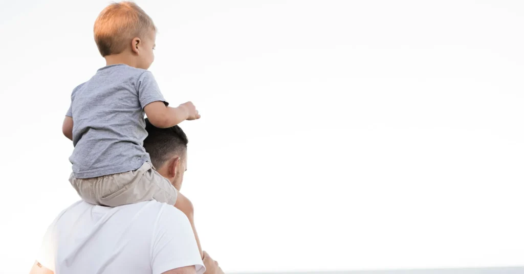 A father holding a child on his shoulders.