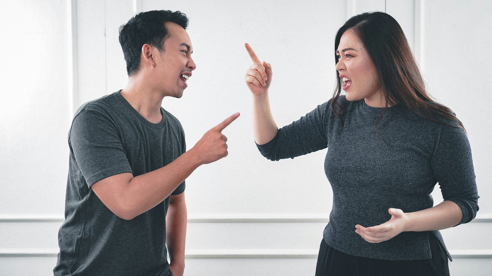 A man and woman argue, pointing at each other, illustrating the tension often found in a loveless marriage.
