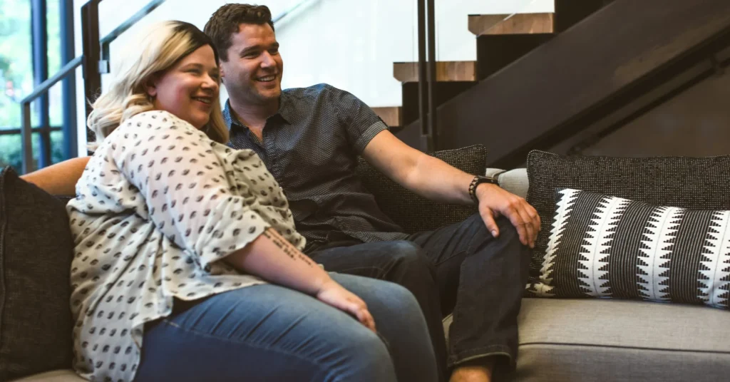 A confident and happy couple sitting on the couch