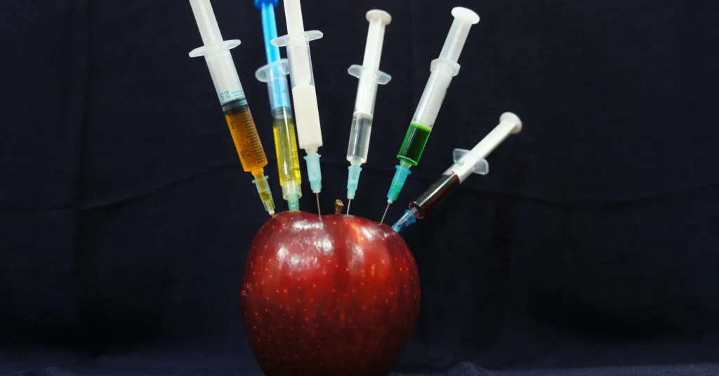 Multiple syringes pinch to the apple which represents the human body with too much medical treatment for looking slim and beautiful.
