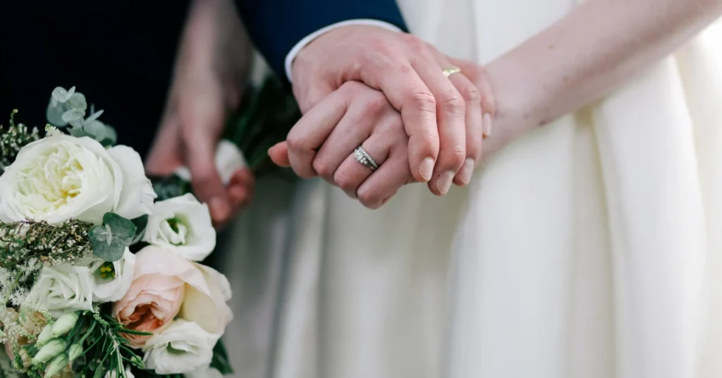 A couple holding each other hands along with a bouquet of flowers and having a faith on God.