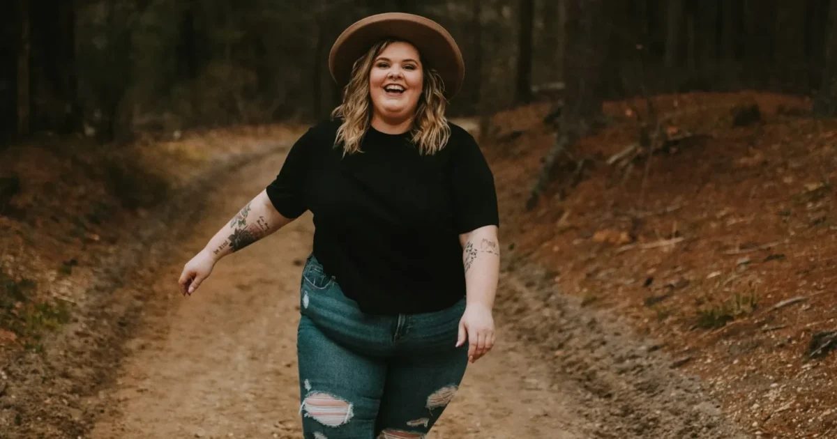An obese lady standing and smiling at the camera