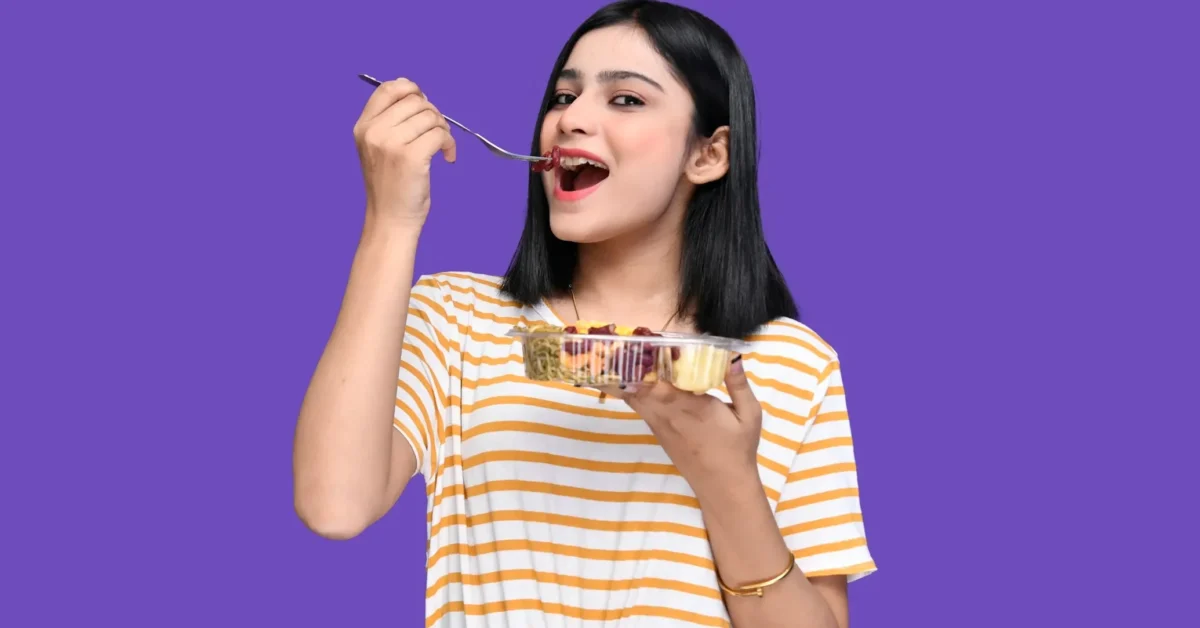 A woman enjoying a bowl of colorful vegetables and fruit , representing the Faster Way to Fat Loss Recipes.