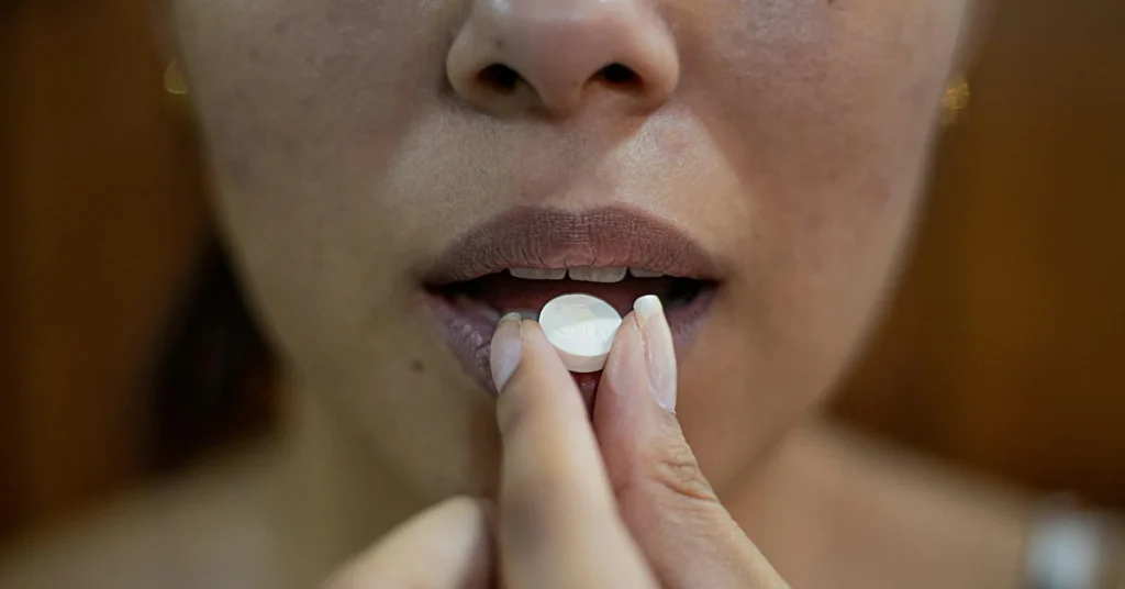 A girl is taking a pill.