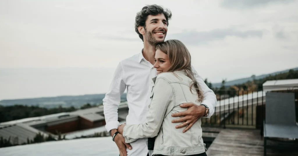 A romantic couple hugging to each other with a smile.