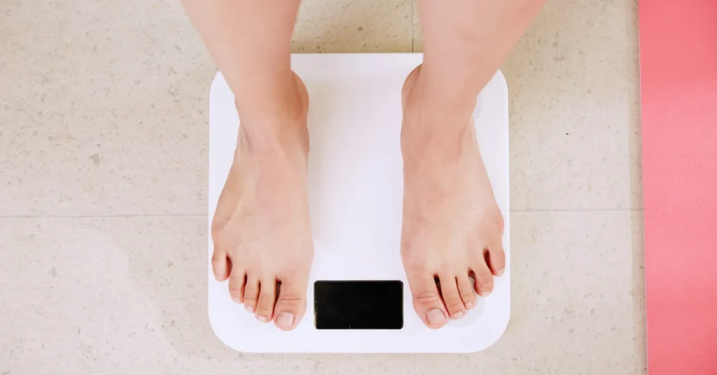 A person standing on the weighing balance for weight calculation.