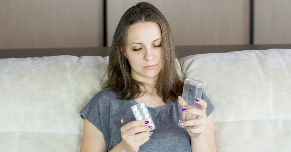An ill lady due to fat malabsorption holding a glass in one hand and medicine in another