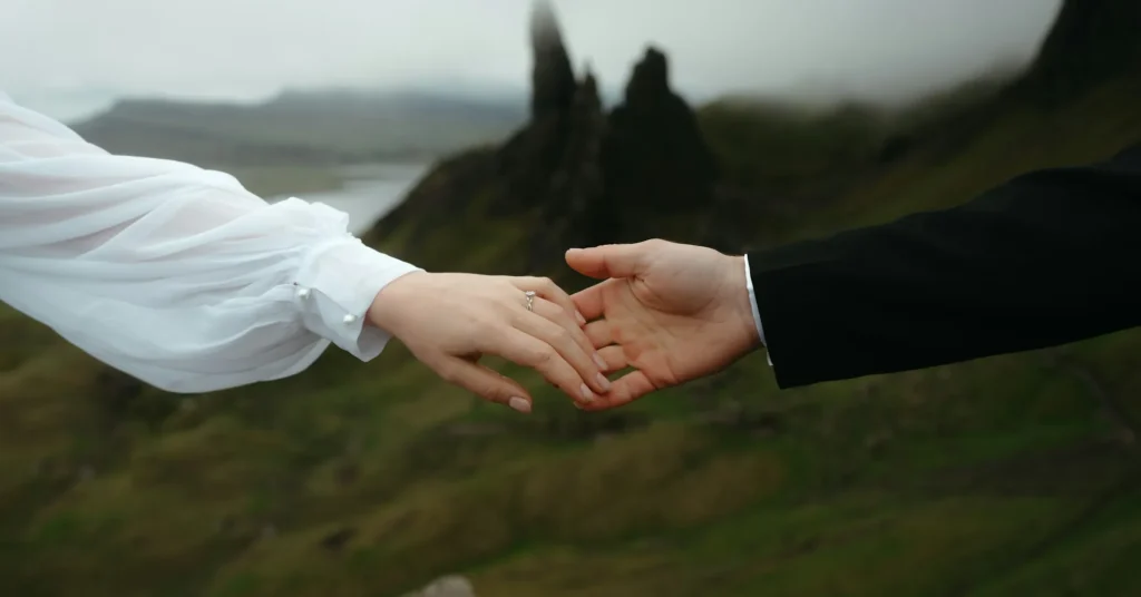 A couple holding each other's hands with a beautiful scene behind it.